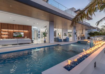 Luxurious modern house with open living space, acrylic swimming pool, and fire feature, ideal for stylish outdoor entertaining.