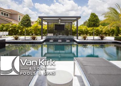 Luxury poolside view with modern pergola, lush greenery, and serene ambiance by Van Kirk & Sons Pools & Spas.