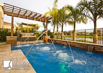 Luxurious backyard pool with fountains, pergola, and palm trees, perfect for relaxation and outdoor entertainment.