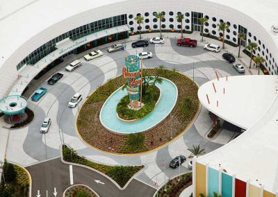 Retro hotel entrance with vintage cars and a mid-century modern design, showcasing a vibrant “Cabana Bay” sign.