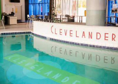 Clevelander Hotel pool area with seating, featuring reflective water and branded signage.