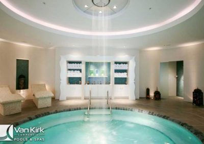 Luxurious indoor spa pool with gentle waterfall, cozy seating, and ambient lighting for ultimate relaxation.