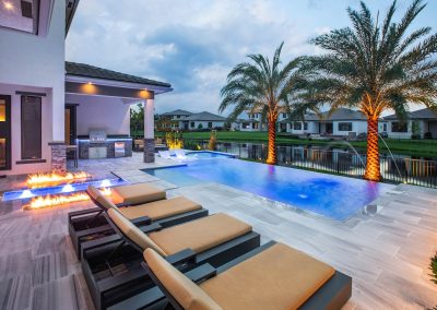 Luxurious backyard with pool, fire pit, and palm trees at sunset. Ideal outdoor living space.