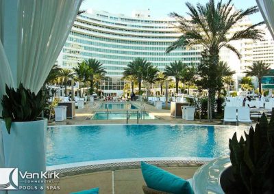 Luxurious poolside setting with palm trees at a modern hotel resort, inviting and relaxing atmosphere.