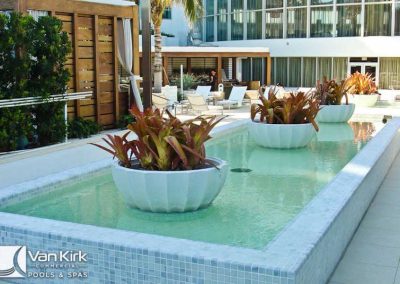 Modern outdoor pool area with elegant planters and seating, designed by Van Kirk Pools & Spas.