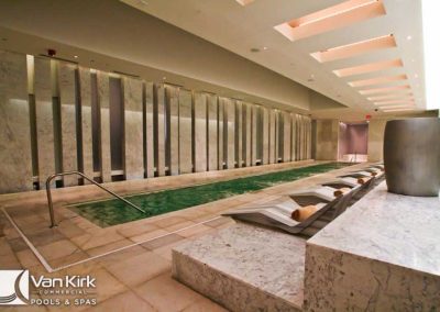 Luxurious indoor spa with pool, loungers, and modern marble decor, reflecting a tranquil and elegant ambiance.