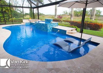 Luxurious backyard freeform pool with modern lounge chairs and waterfall feature under a screened enclosure.