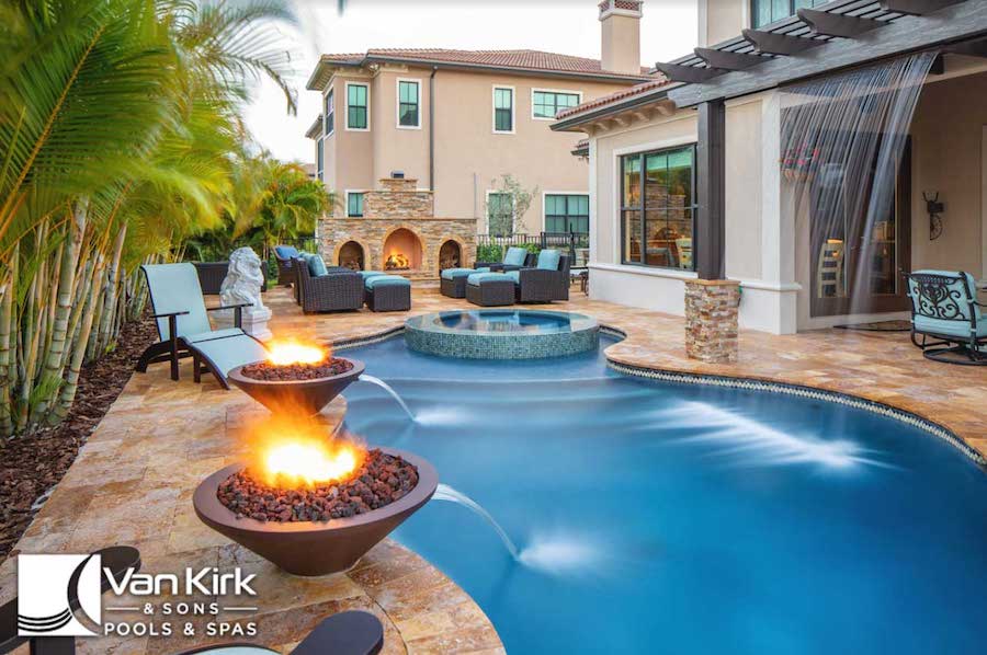 Luxurious backyard with lagoon pool, fire features, seating area, and cascading water design for relaxation and entertainment.