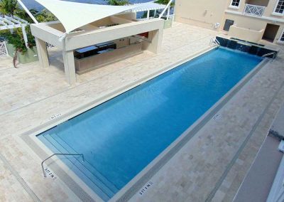 Wide view of a modern outdoor pool with shaded seating area, showcasing luxury relaxation and refreshing swim facilities.