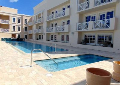 Modern hotel with outdoor pool and balconies on a sunny day, perfect for a relaxing vacation.