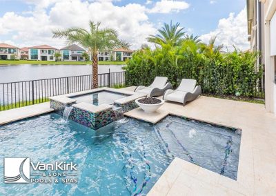 Luxurious backyard pool and spa with lounge chairs by Van Kirk & Sons, overlooking a serene waterfront landscape.