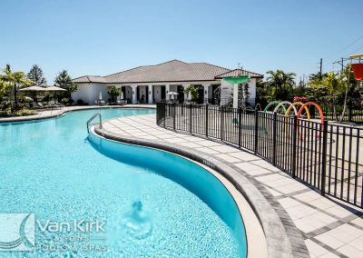 Luxury resort-style swimming pool with lounge area and palm trees on a sunny day.