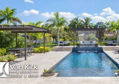 Modern backyard pool with palm trees, pergola, and shaded seating area, designed by Van Kirk & Sons Pools & Spas.