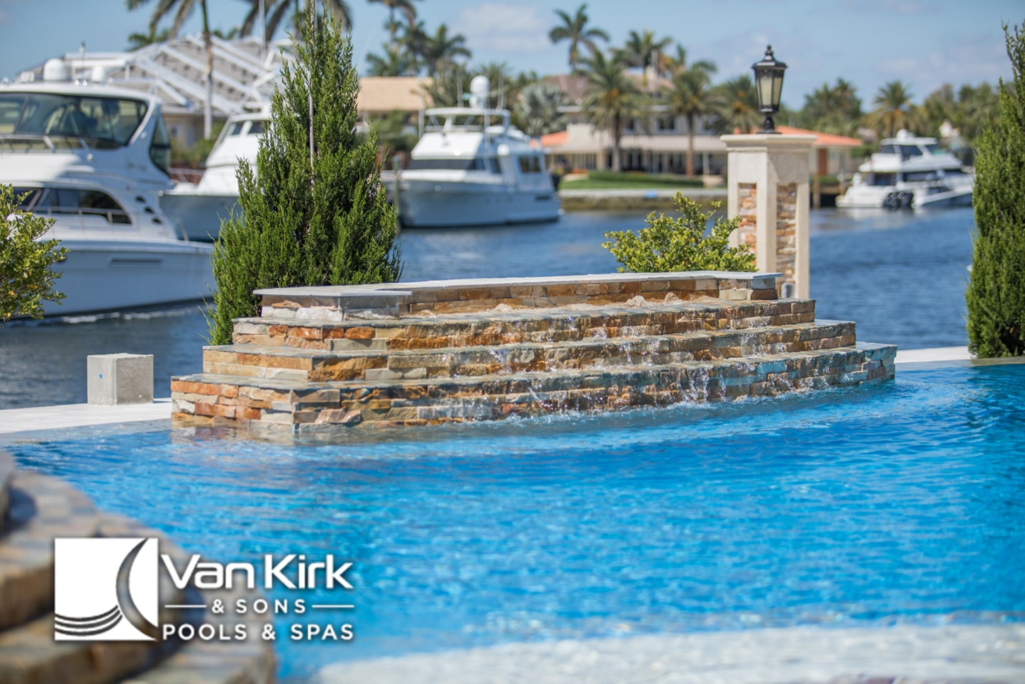 Luxurious pool with stone raised wall waterfall near marina, by Van Kirk & Sons Pools & Spas.