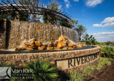 Illuminated waterfall feature and landscaping at the Riverstone community entrance in Naples.