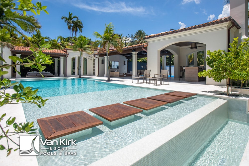Luxurious modern pool with stepping stones and tropical landscaping at a stylish home, designed by Van Kirk & Sons.
