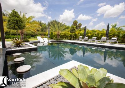 Luxurious outdoor pool area with palm trees, swim up bar, lounge chairs, and modern design.