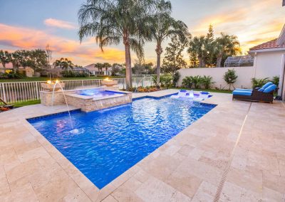 Luxurious backyard straight line pool with spa, water features, and palm trees at sunset. Ideal outdoor oasis for relaxation.