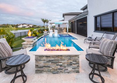 Luxurious modern backyard with pool, fire feature, and lounge chairs, perfect for stylish outdoor relaxation.