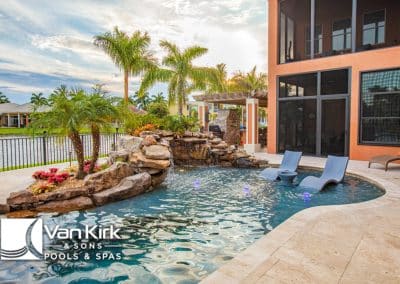 Luxurious backyard pool with spa, waterfall, and palm trees by Van Kirk & Sons. Perfect for relaxation and enjoyment.