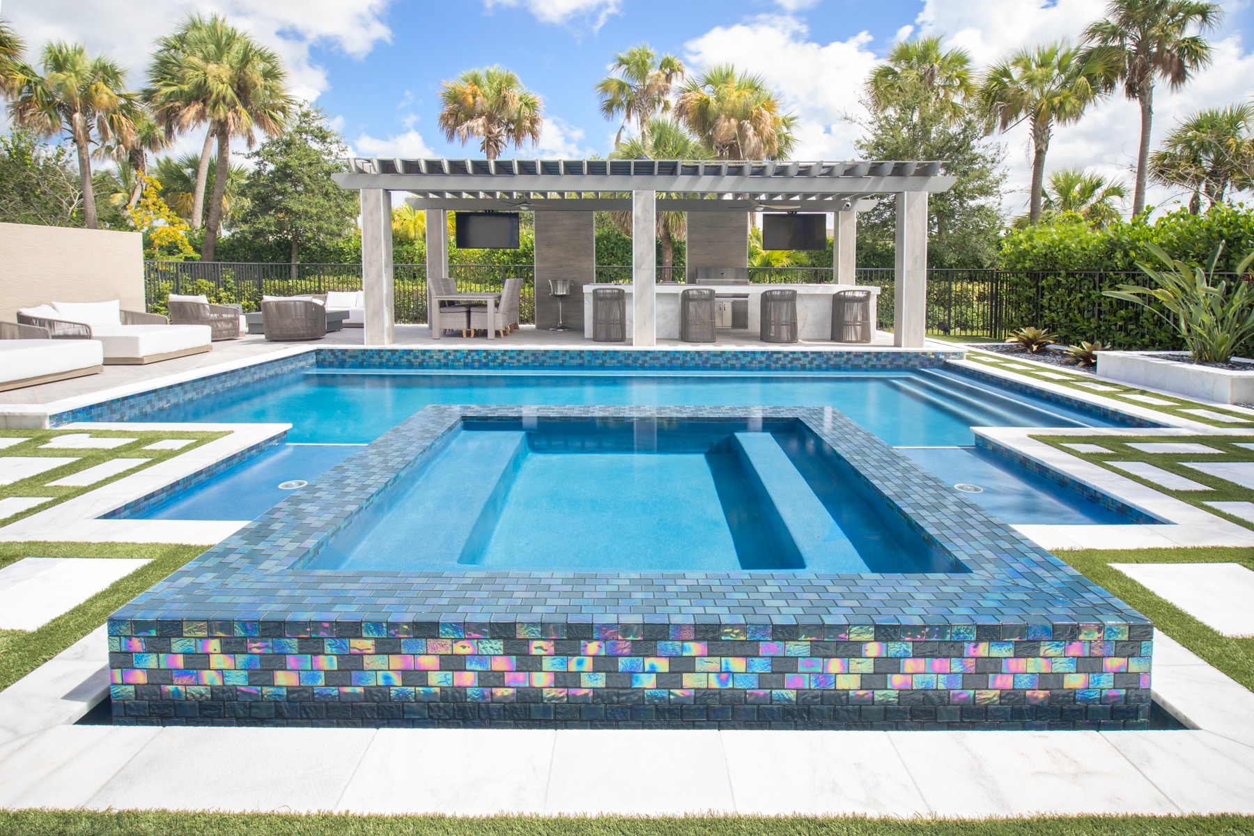 Luxurious outdoor pool designed by Fort Lauderdale pool contractor Van Kirk & Sons with modern seating area, palm trees, and pergola, perfect for relaxation and entertainment.