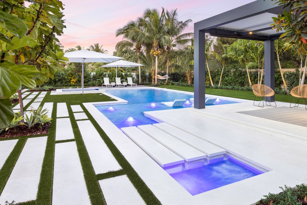 Modern poolside with lounge chairs, palm trees, and ambient lighting at sunset in Fort Lauderdale, Florida. Luxurious outdoor relaxation space.