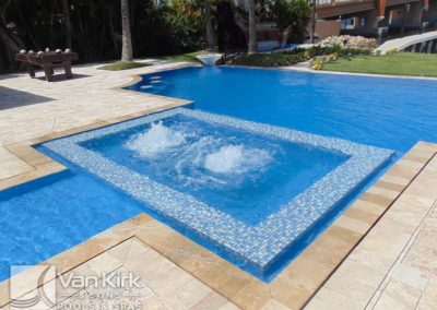 Luxurious backyard pool with jacuzzi area and elegant tile design, surrounded by tropical landscaping in north palm beach