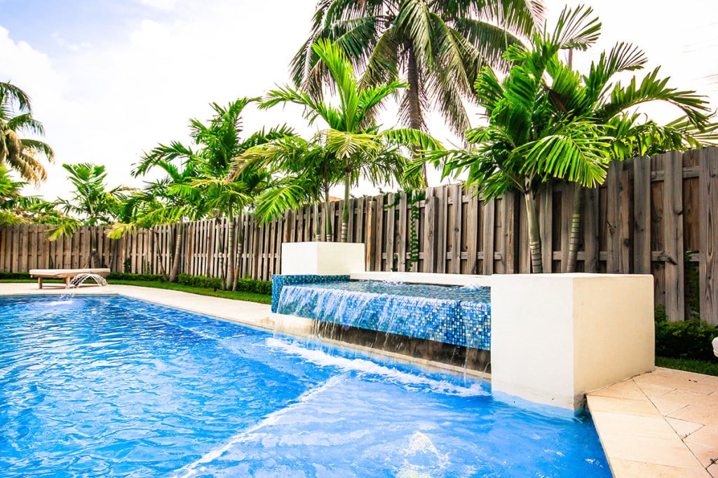 Luxurious Wellington, Florida backyard pool with cascading waterfall and palm trees, creating a tropical oasis ambiance.