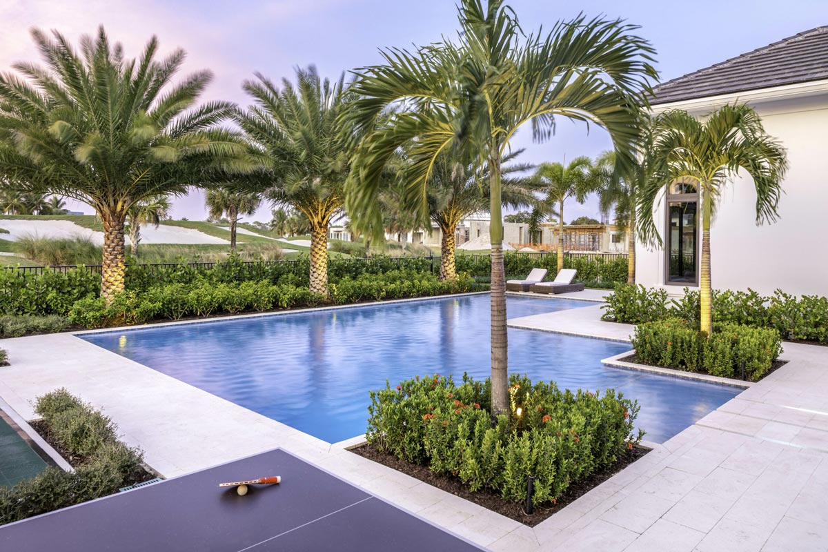 Luxury backyard in Weston, Florida with palm trees, a modern pool, sun loungers, and a ping pong table at sunset.