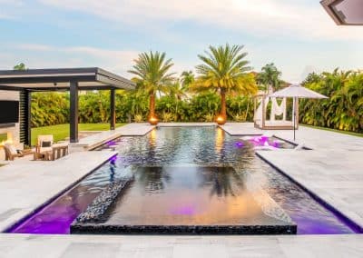 luxury geometric infinity pool with fire bowls and modern outdoor lounge.