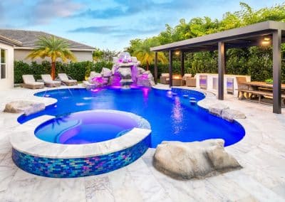 Lagoon pool with rock waterfall, raised spa, and outdoor kitchen area.
