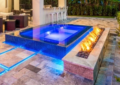 Raised spa with blue tile, fire feature, and LED lighting beside modern patio.