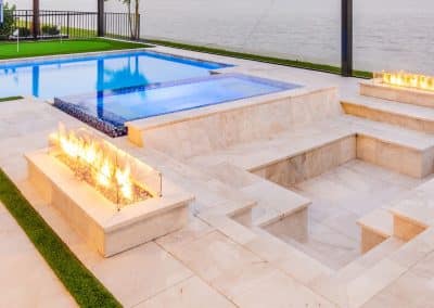 Linear pool with raised spa and sunken fire conversation pit under screened enclosure.