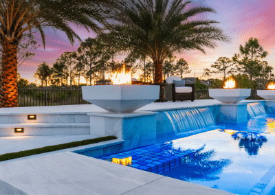 A custom pool with elegant fire bowls and sheer descent waterfalls in Lotus Palm.