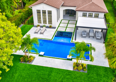 Aerial view of a modern geometric pool with a raised spa and a custom patio in Loxahatchee.