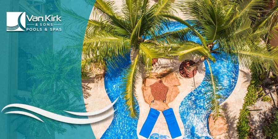An aerial view of a custom lazy river pool winding through a tropical landscape with palm trees in Palm City.