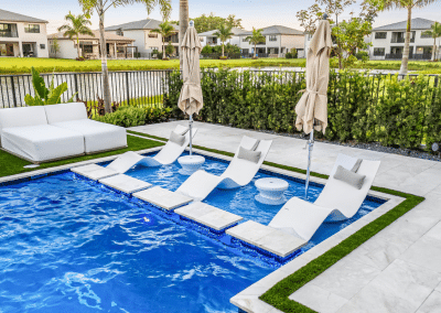 Custom modern geometric pool with a spacious sun shelf and in-pool lounge chairs in Westlake, Florida.