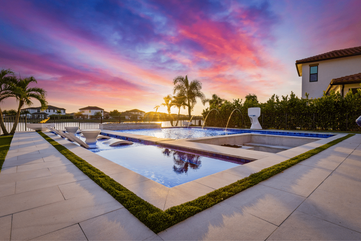 Custom modern geometric pool with a raised spa, deck jets, and in-pool lounge chairs in Wellington.