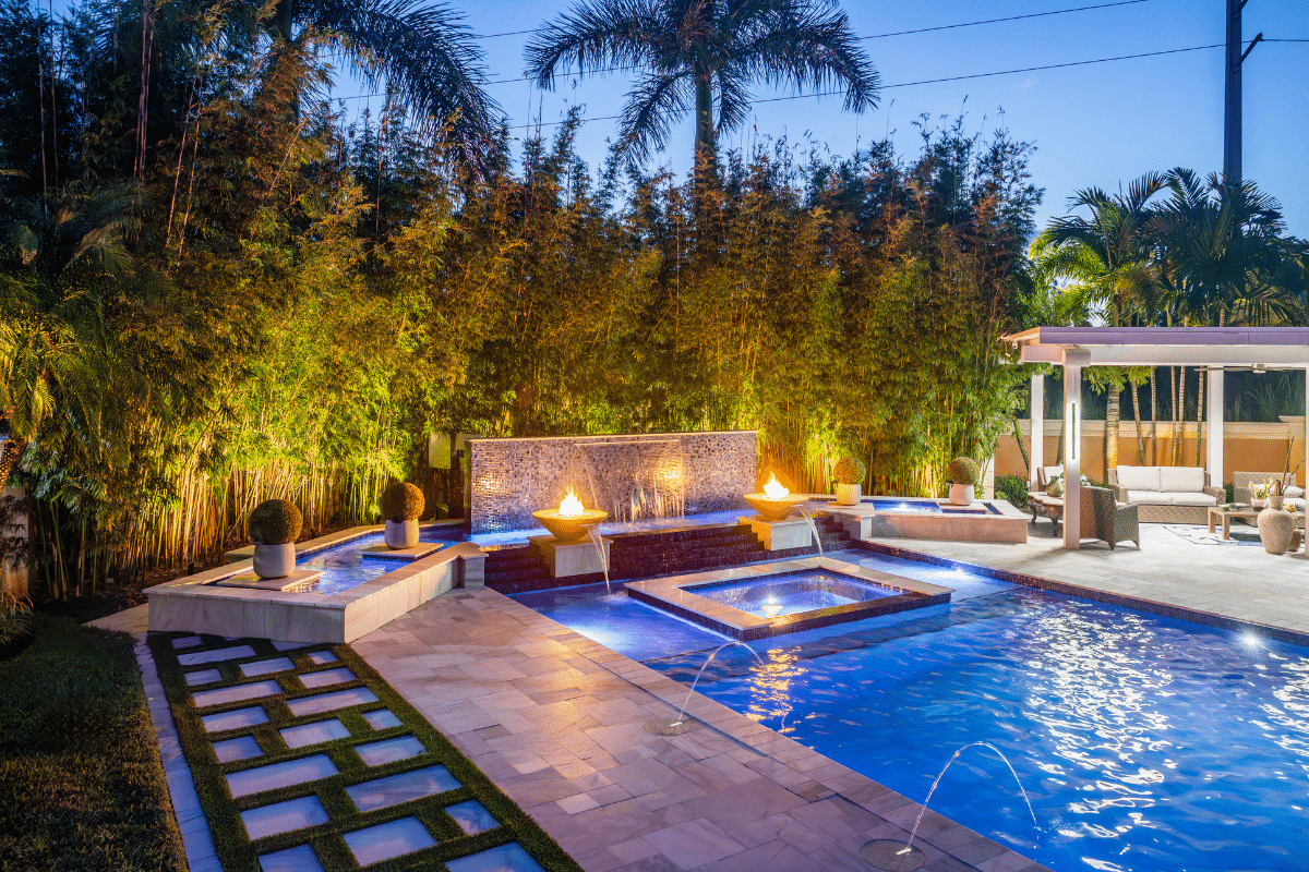 Custom modern geometric pool with a raised spa, fire bowls, and a waterfall wall in Davie.