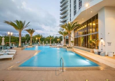 The commercial resort pool at The Harbour in North Miami Beach, built by Van Kirk Pools, glows with underwater lighting at twilight.