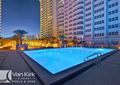 The commercial lap pool at Southpoint Condominiums, built by Van Kirk Pools, glows with cyan LED lighting at night in Fort Lauderdale.