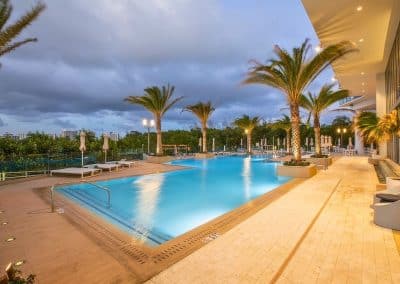 The commercial resort pool at The Harbour, built by Van Kirk Pools, is illuminated by underwater and landscape lighting at twilight.
