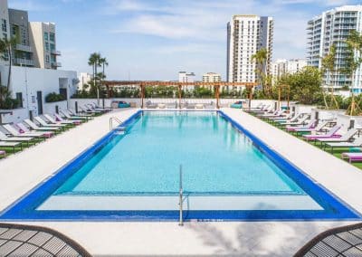 Eye-level view of the large rectangular commercial pool in Downtown Fort Lauderdale, featuring a blue tiled edge and white sundeck.