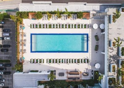 Direct overhead aerial view of the rectangular commercial pool, sun deck, and surrounding parking and street access in Downtown Fort Lauderdale.