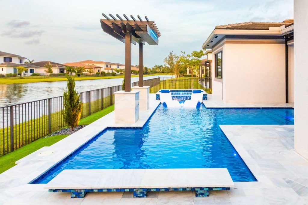Elegant straight-line geometric pool design with a sleek pergola, sun shelf loungers, and spa area overlooking a lake.