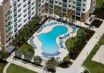 Aerial view of the resort-style freeform pool at Innovation Village Apartments (IVA) featuring a pool basketball hoop and lounge seating, by Van Kirk & Sons.