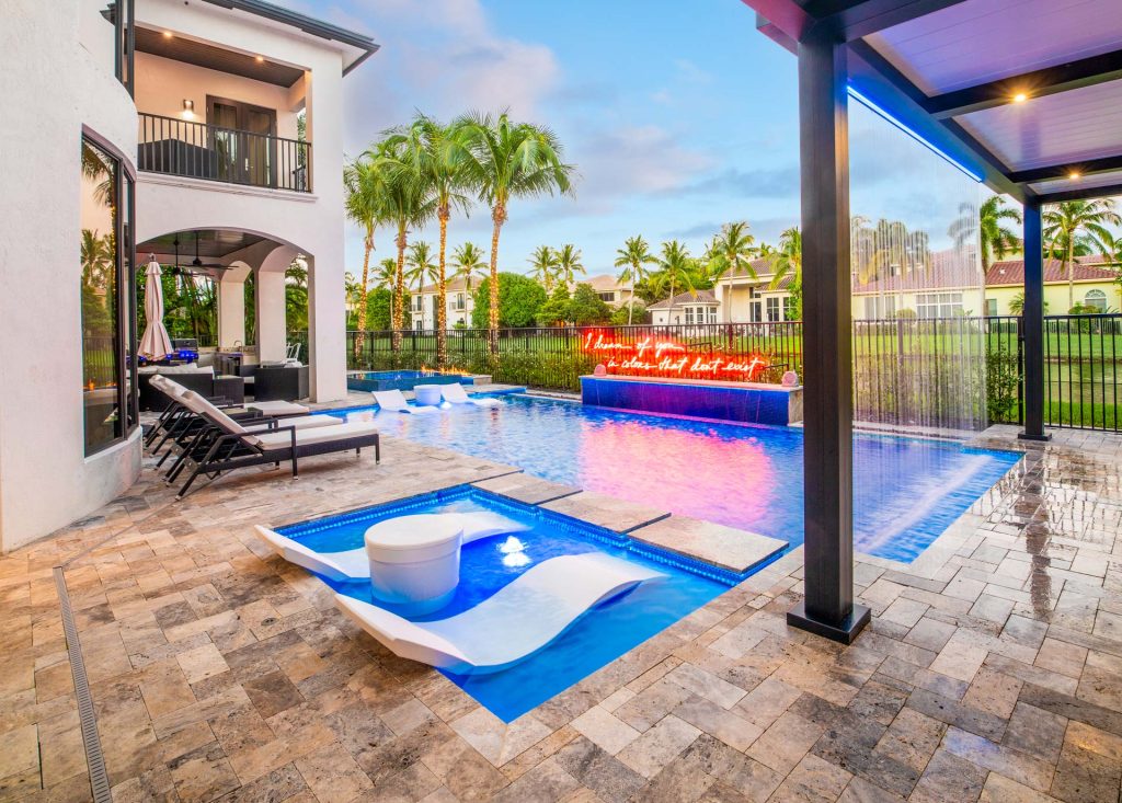 Modern swimming pool with a sun shelf, rain curtain water feature, and lounge chairs