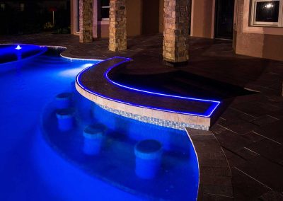 A close-up of the custom swim-up bar with blue LED lighting and in-pool stools, built by Van Kirk Pools for "The Vanilla Ice Project."