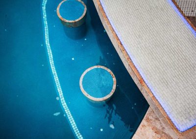 An aerial close-up of the custom in-pool stools and the LED-lit swim-up bar from "The Vanilla Ice Project" pool by Van Kirk.