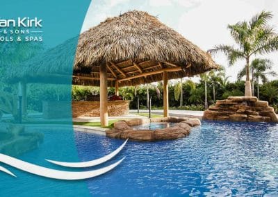A tropical pool in Palm Beach built by Van Kirk Pools for The Vanilla Ice Project, featuring a large tiki hut, an outdoor kitchen, and a rock spa.